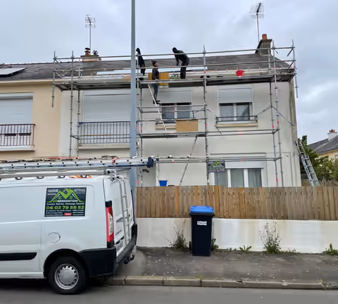 Le camion de DN Rénovation devant une maison échafaudée, deux couvreurs au travail sur le toit
