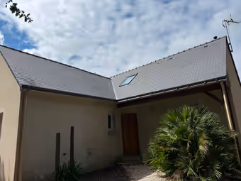 Maison dont les deux pans de toiture viennent d’être refaits, fenêtre de toit et rives métalliques posées