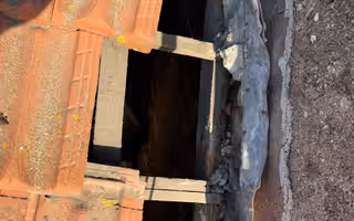 Tuiles déposées le long d’un mur de pierre, ouverture béante sur les liteaux et le vide sous la couverture